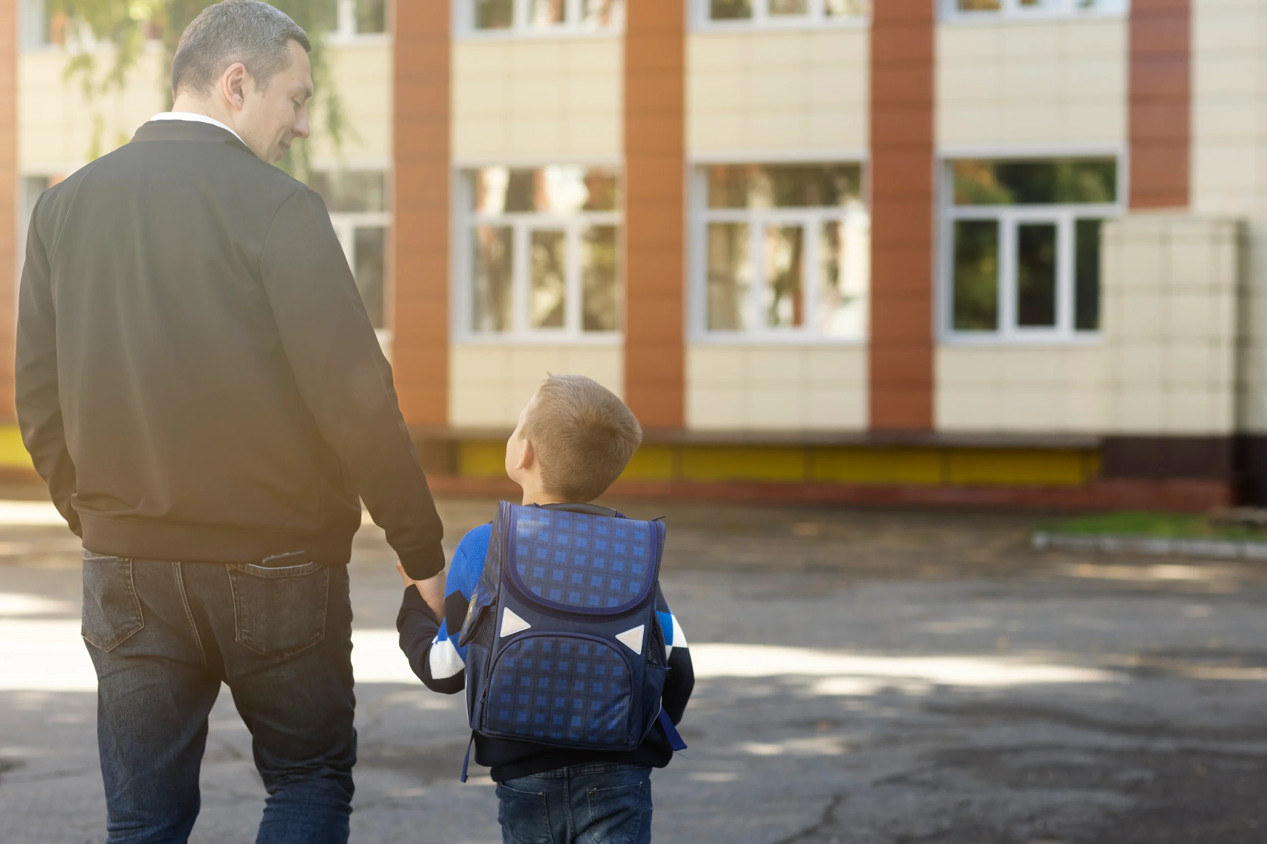 Père et son fils se tenant la main devant l'école